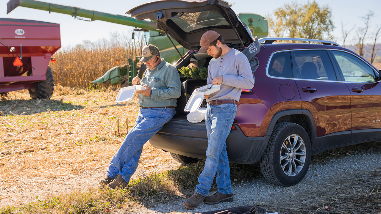 Two farmers sitting on tailgate.