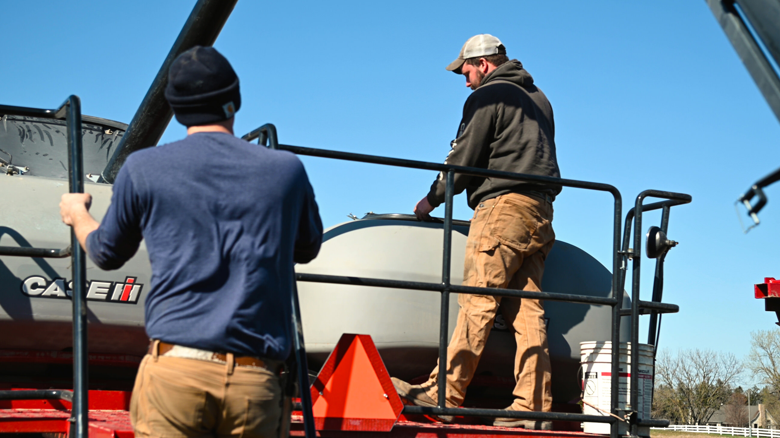 Photo of two farmers working on machinery.