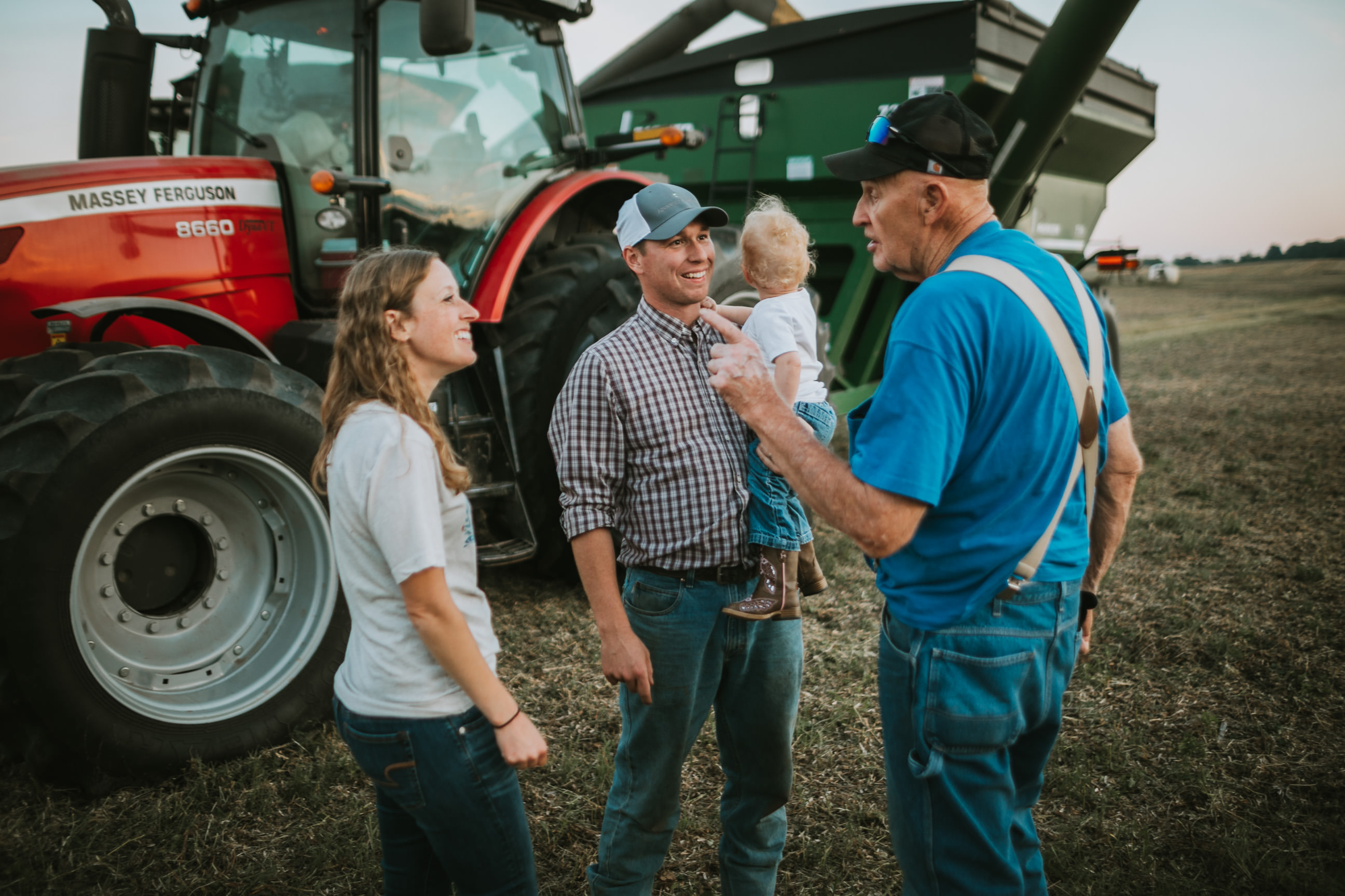 Farmers talking outside of tractor in the field.