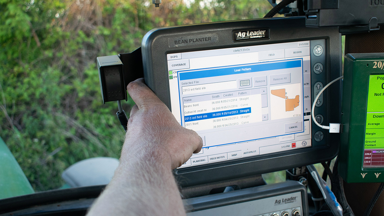 Closeup photo of a person operating a planter monitor in the cab of a planter.