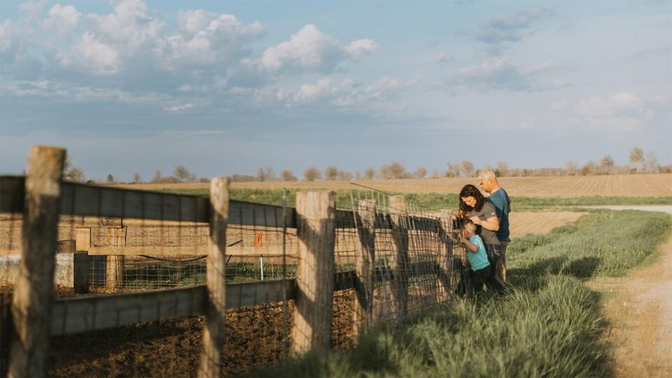 Family at fence in field.