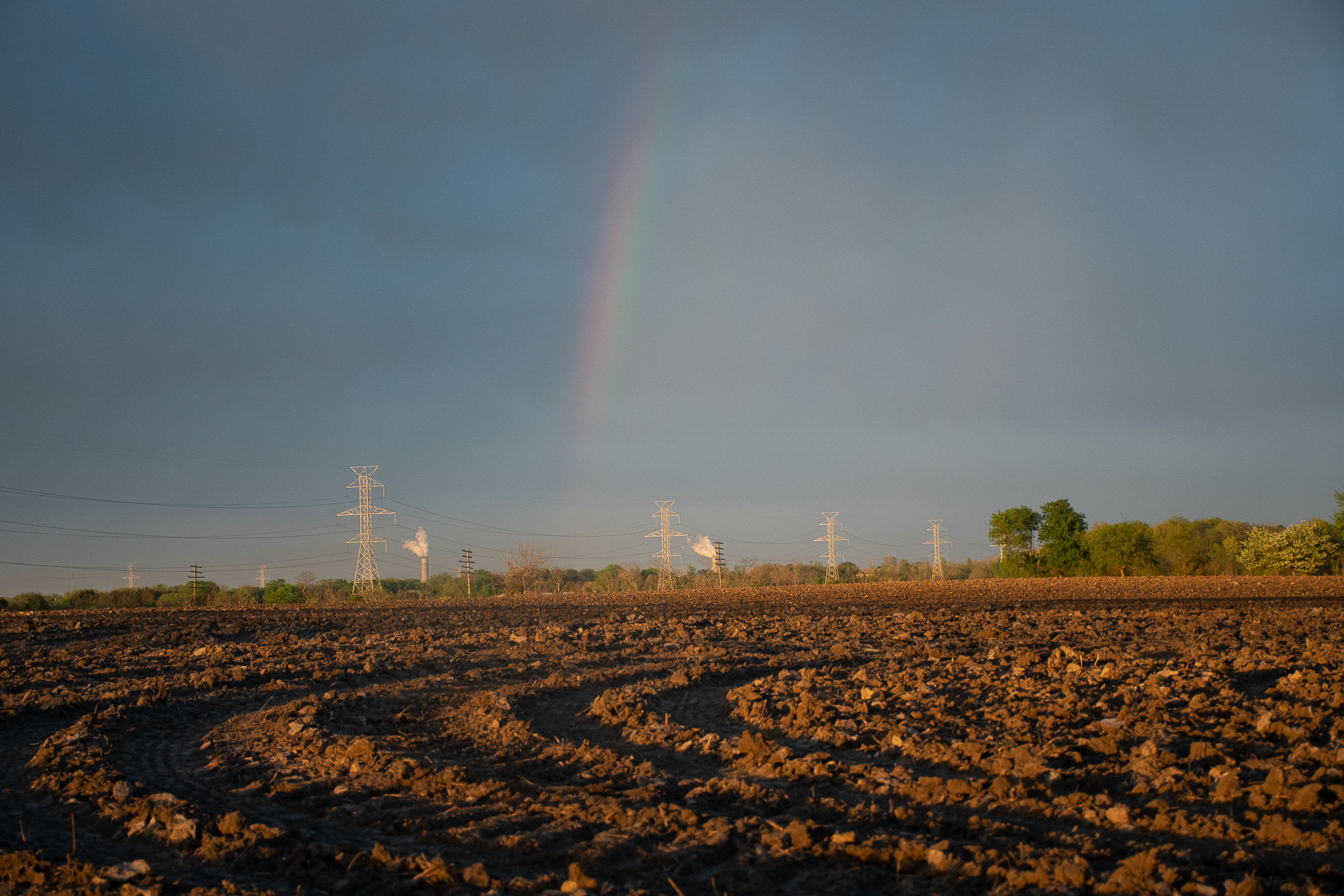 Photo of farmland with a rainbow in the background.