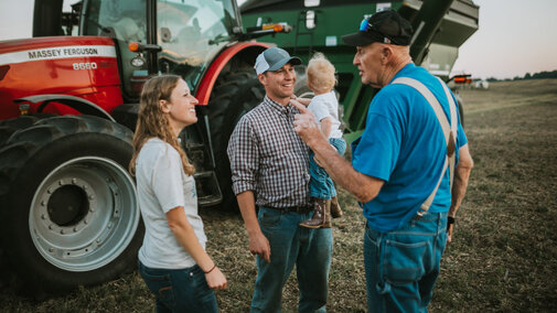 Farmers talking outside of tractor in the field.