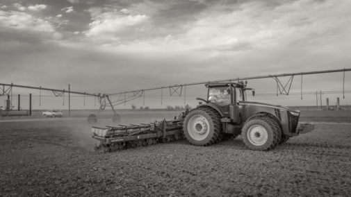 A tractor with an implement sits in a field amid a center pivot.