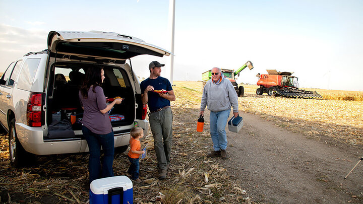 Farm family eating lunch in field.