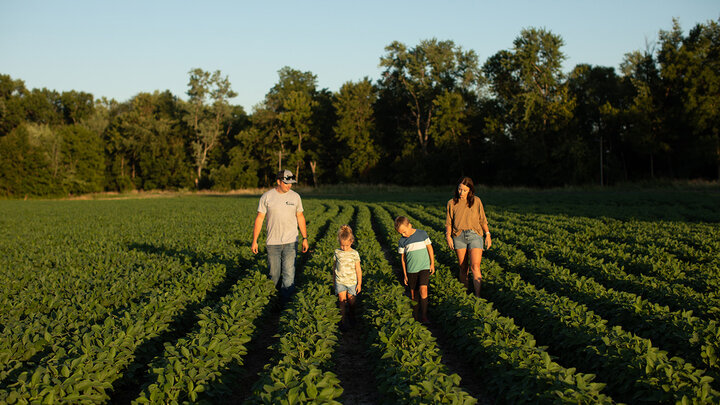 Young farm family walking in field