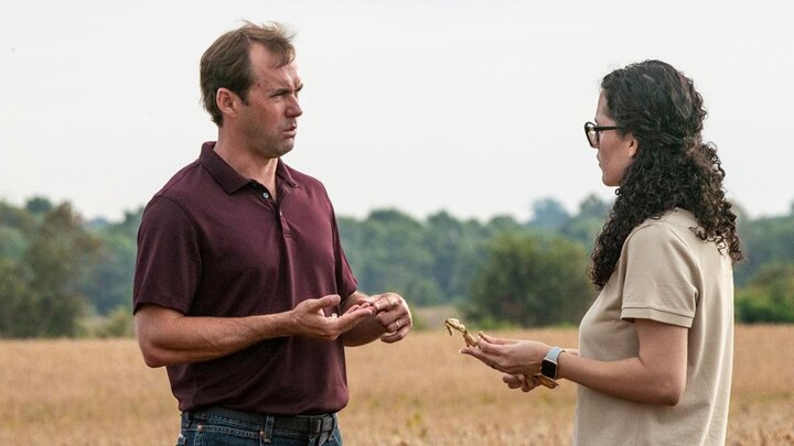 Two people talking in field.