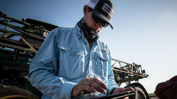 Farmer working on an ipad outside of sprayer.