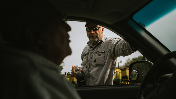 Multiple Farmer Generations Talking through a pickup's window.