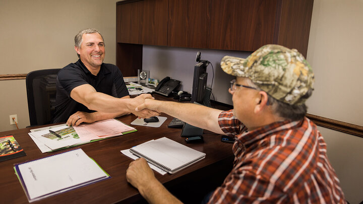 Farmer meeting with business person in office.