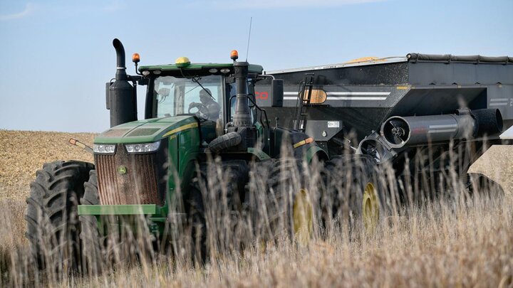 Photo of tractor pulling cart in a field.