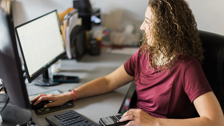 Photo of a female farmer working at a computer.
