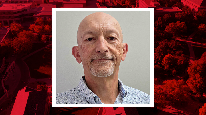 A portrait of David Haupt set against a red-tinted aerial view of buildings and trees.