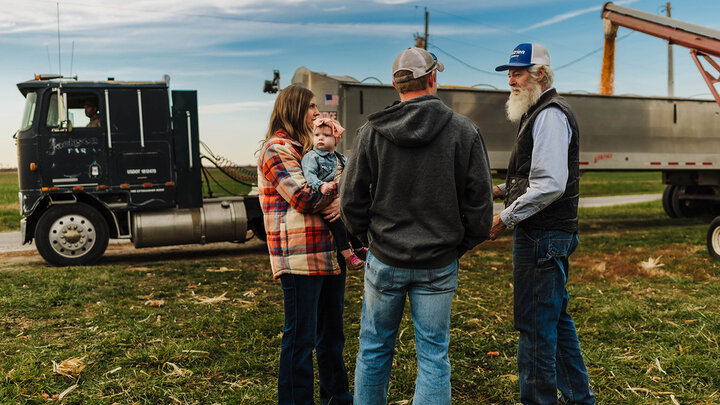 Photo a multigenerational farm family talking as a grain truck is loaded..