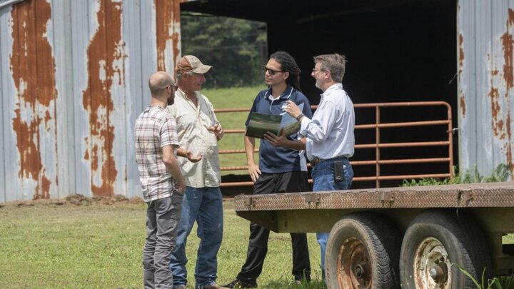 Farmers talking in front of barn.