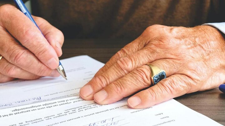 Closeup of hand signing documents with a pen.