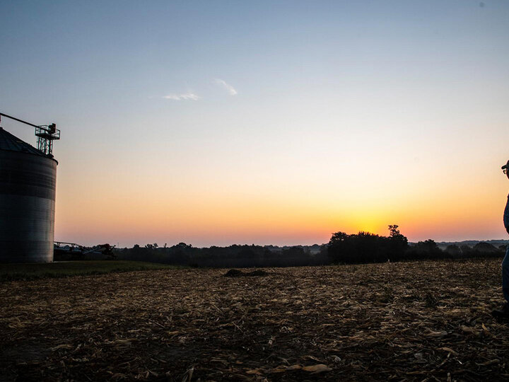 Man near grain bins at dusk.