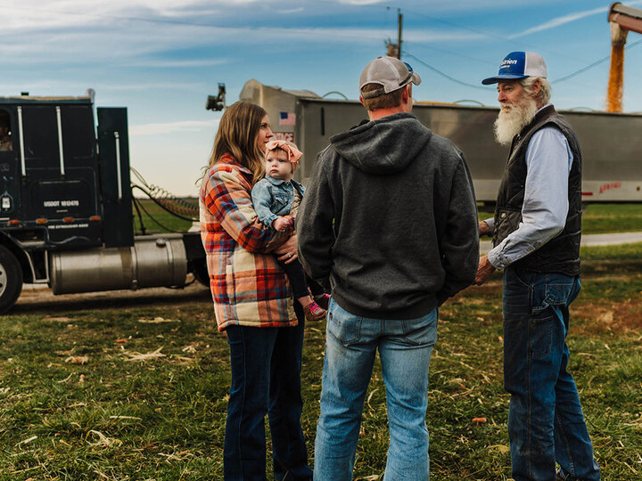 Photo a multigenerational farm family talking as a grain truck is loaded..