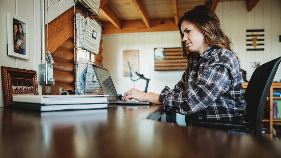 Photo of a woman working on a computer at a desk.