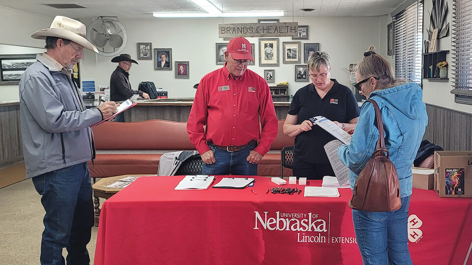 Photo of Nebraska Extension personnel at a table in the lobby of a sale barn.