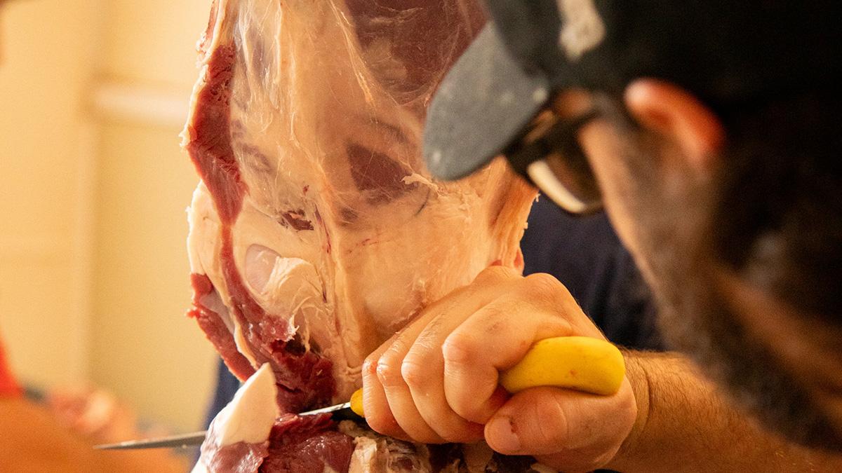 Closeup of man cutting raw beef.