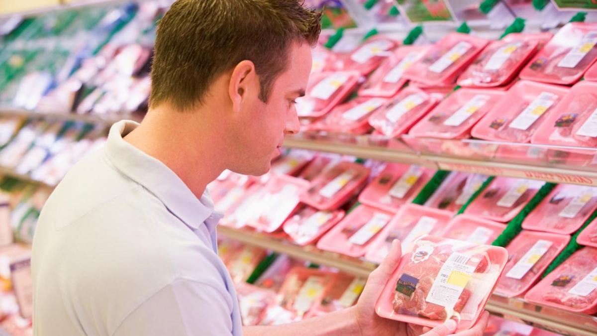 Man shopping the meat section at grocery store.