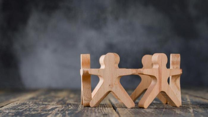 Wooden figures of people holding hands on table.