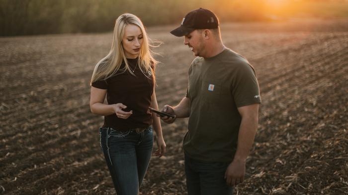  Young Couple Look at Phone in Field at Sunset