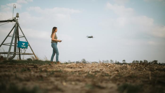 Woman flying drone in field.